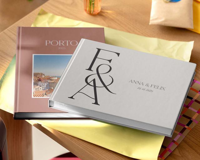 Dois álbuns de fotos personalizados numa mesa, em tamanhos e designs diferentes.