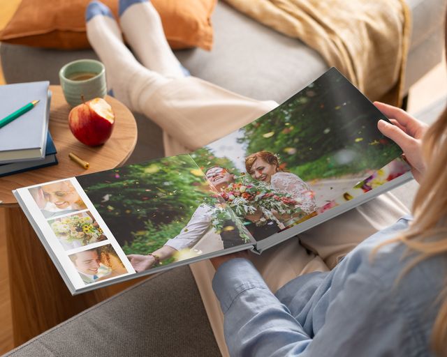 Mulher a olhar para um livro de fotografias plano aberto com fotografias de um casamento.