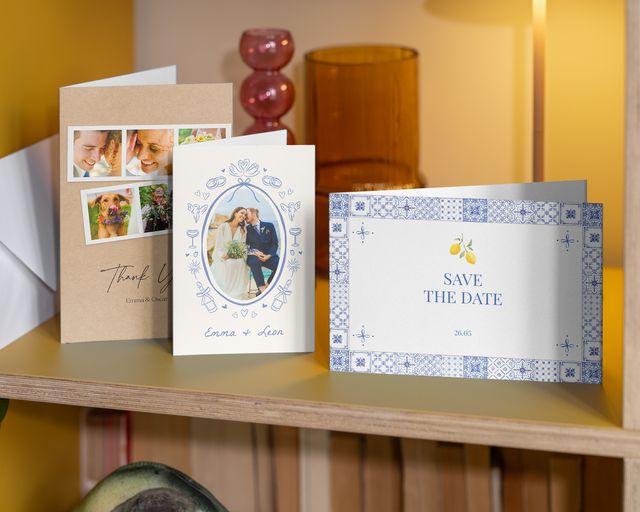 Três postais fotográficos de casamento numa prateleira: um para reservar a data e dois de agradecimento.