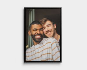 Impressão em tela com moldura preta, de dois homens a sorrir.