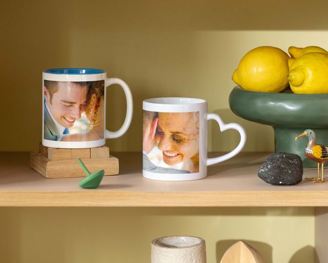 Duas canecas personalizadas com fotos de casamento, uma com uma pega em forma de coração.